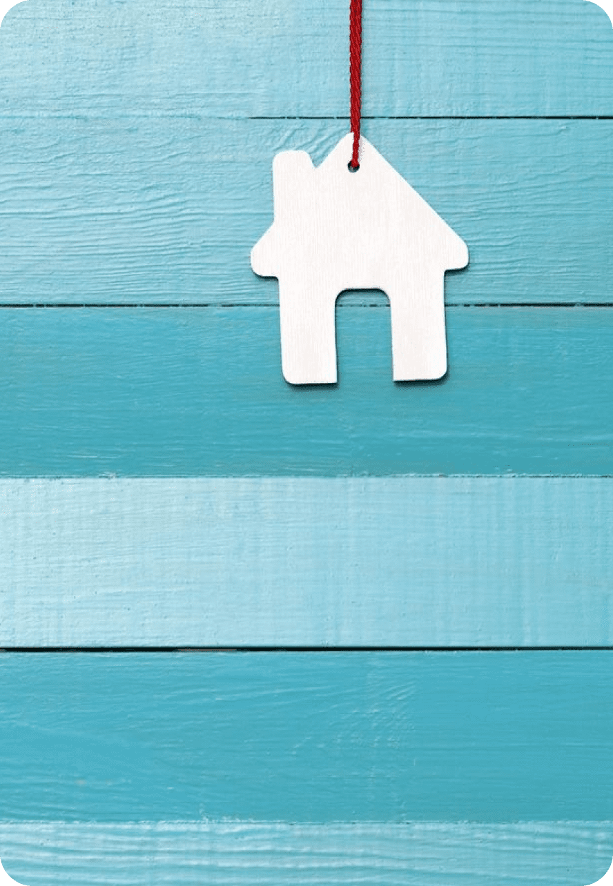 White house-shaped keychain on blue wooden background.