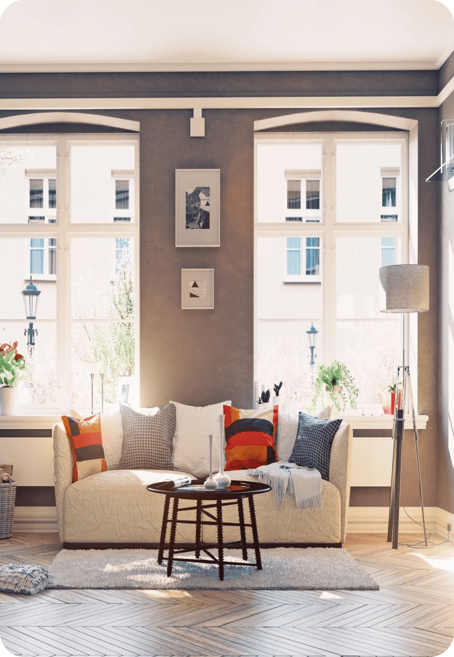 Cozy living room with large windows, a beige sofa, and decorative cushions.