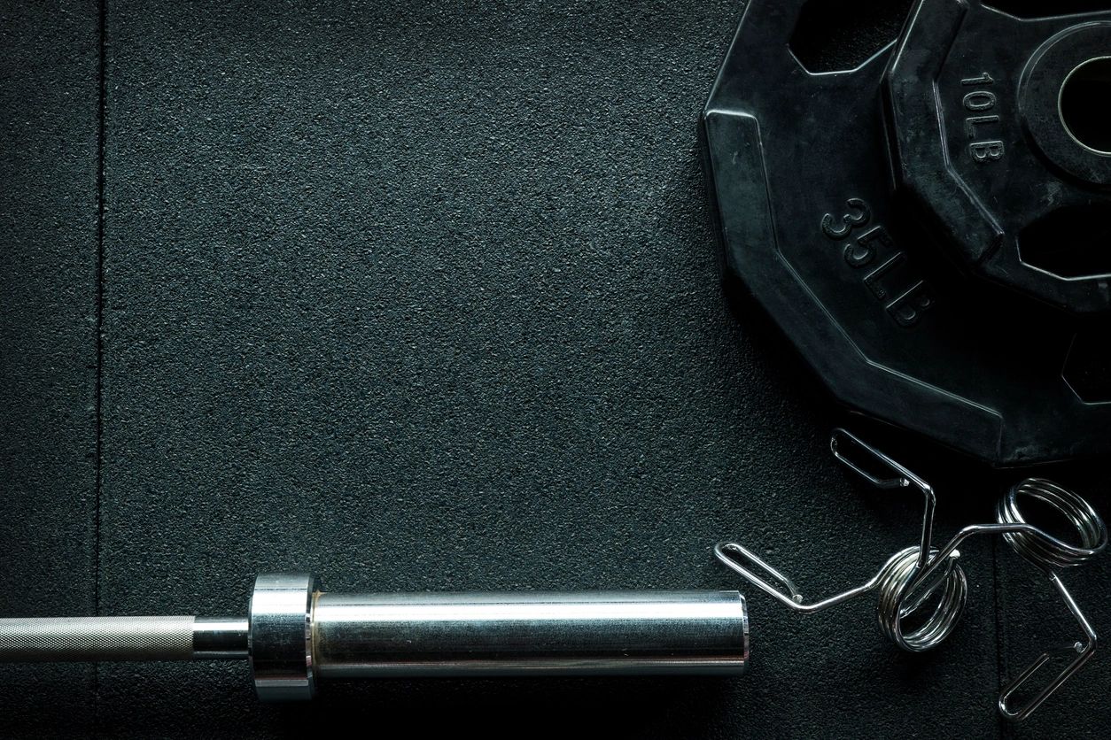 Close-up of a dumbbell weight and lifting bar on a dark surface.